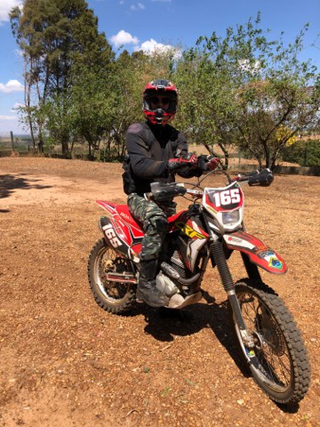 Rider on a red enduro motorcycle on a dirt track in the Brazilian interior