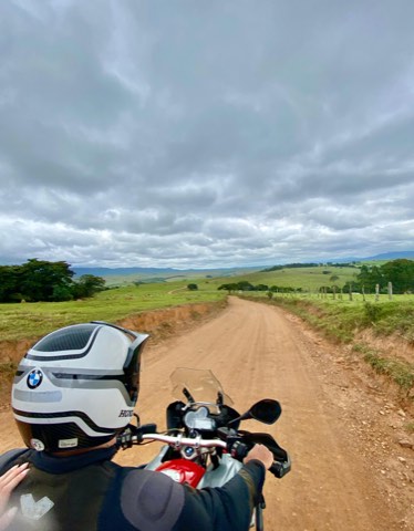 Adventure motorcycle on a red dirt road in Carrancas, Minas Gerais, under a storm sky