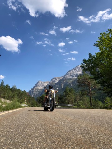 Motorcycle on a mountain road below jagged peaks in the Val d Aran