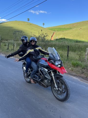 Piloto y pasajero en una moto trail roja por una carretera comarcal a las afueras de Río de Janeiro