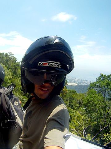 Piloto y pasajero en una moto por una carretera de bosque sobre Río de Janeiro