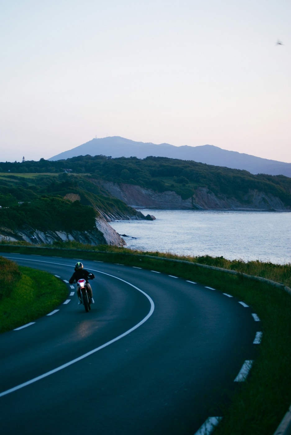 Motorcycle on a sweeping coastal road at dusk