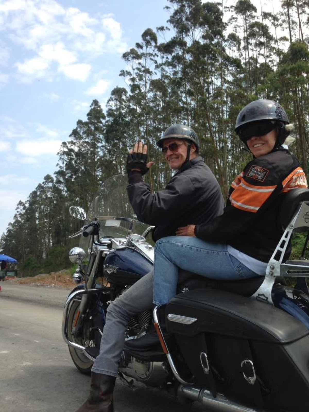 Pilot and passenger waving from a touring motorcycle