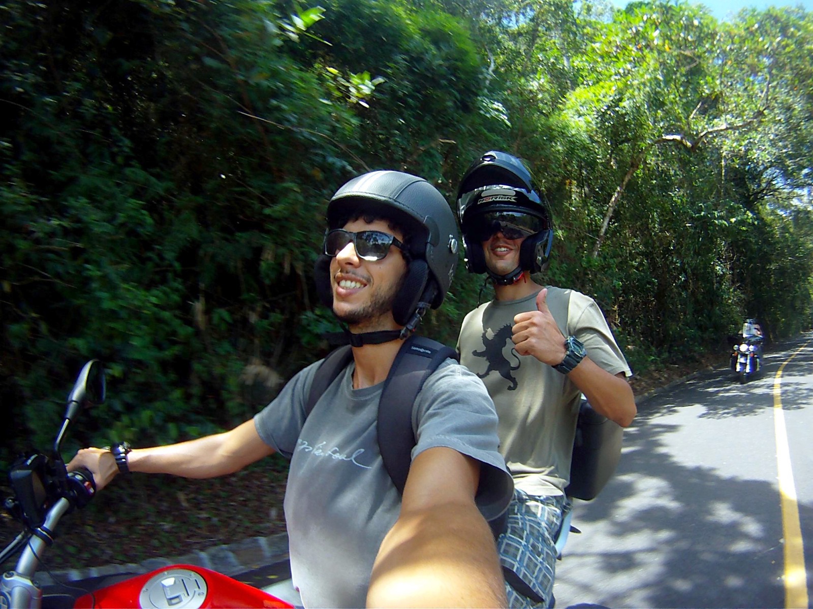 Pilot and passenger smiling on a motorcycle on a forest road